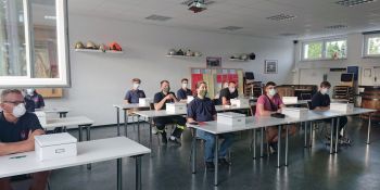 Teilnehmerinnen und Teilnehmer im Unterrichtsraum mit Mund-Nasen-Schutz